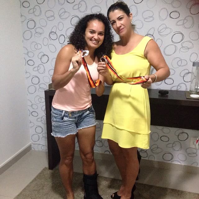 Atleta acompanhada por Claudia Guimarães exibindo medalhas de competição